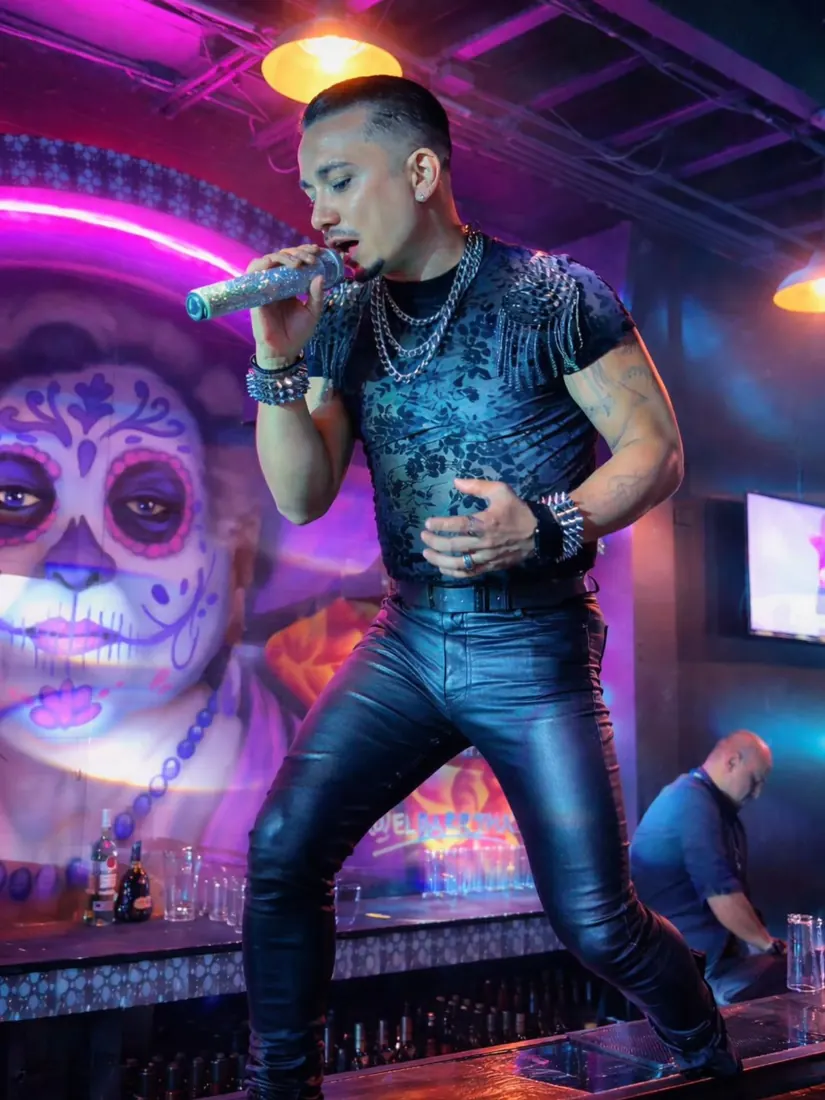 Pedro cantando con pantalón de cuero y camisa con brillo