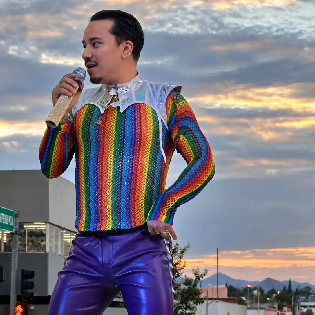 Vocalista con suéter arcoíris cantando al atardecer