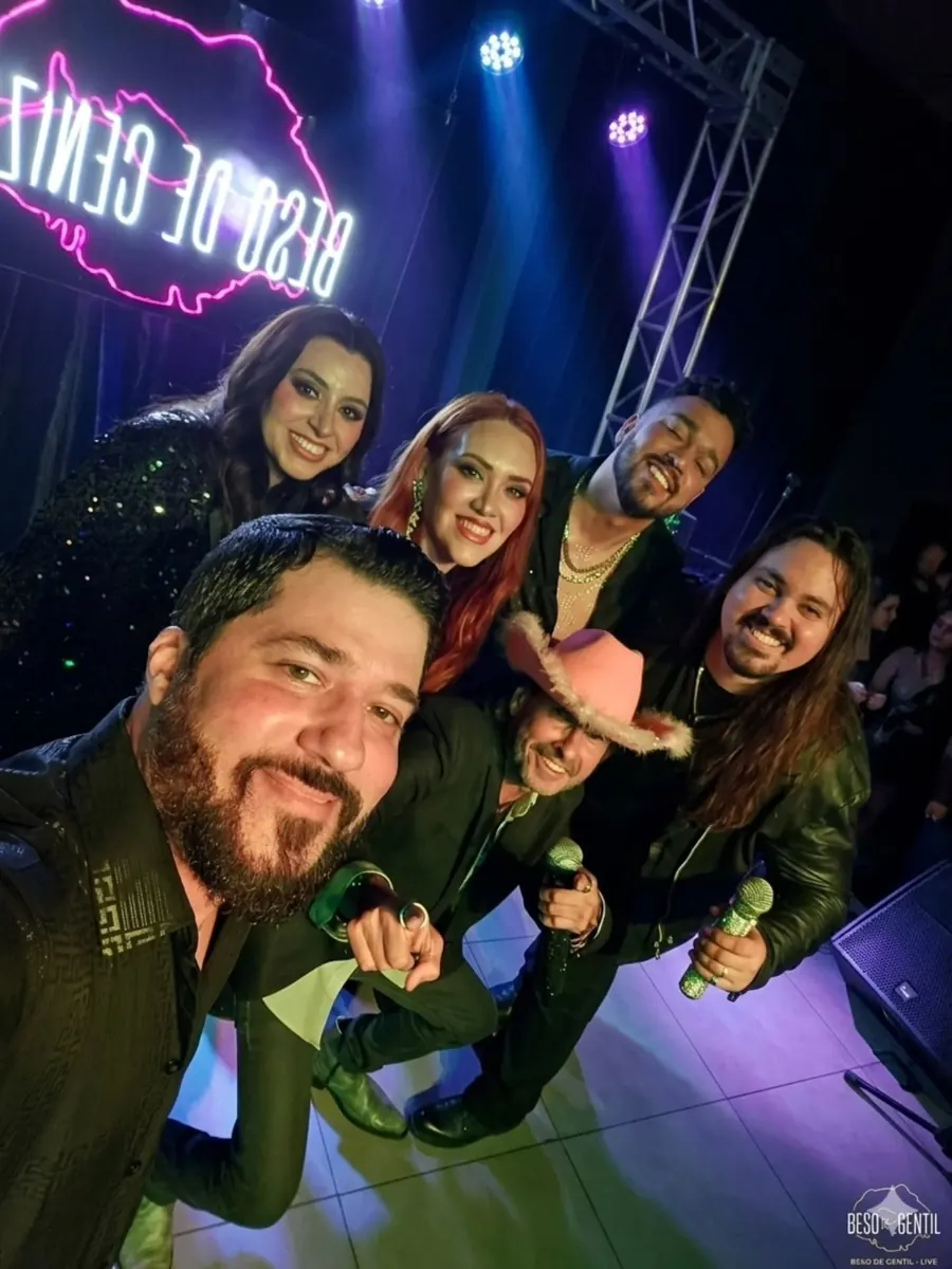 Selfie del grupo desde el escenario con el letrero de neón detrás