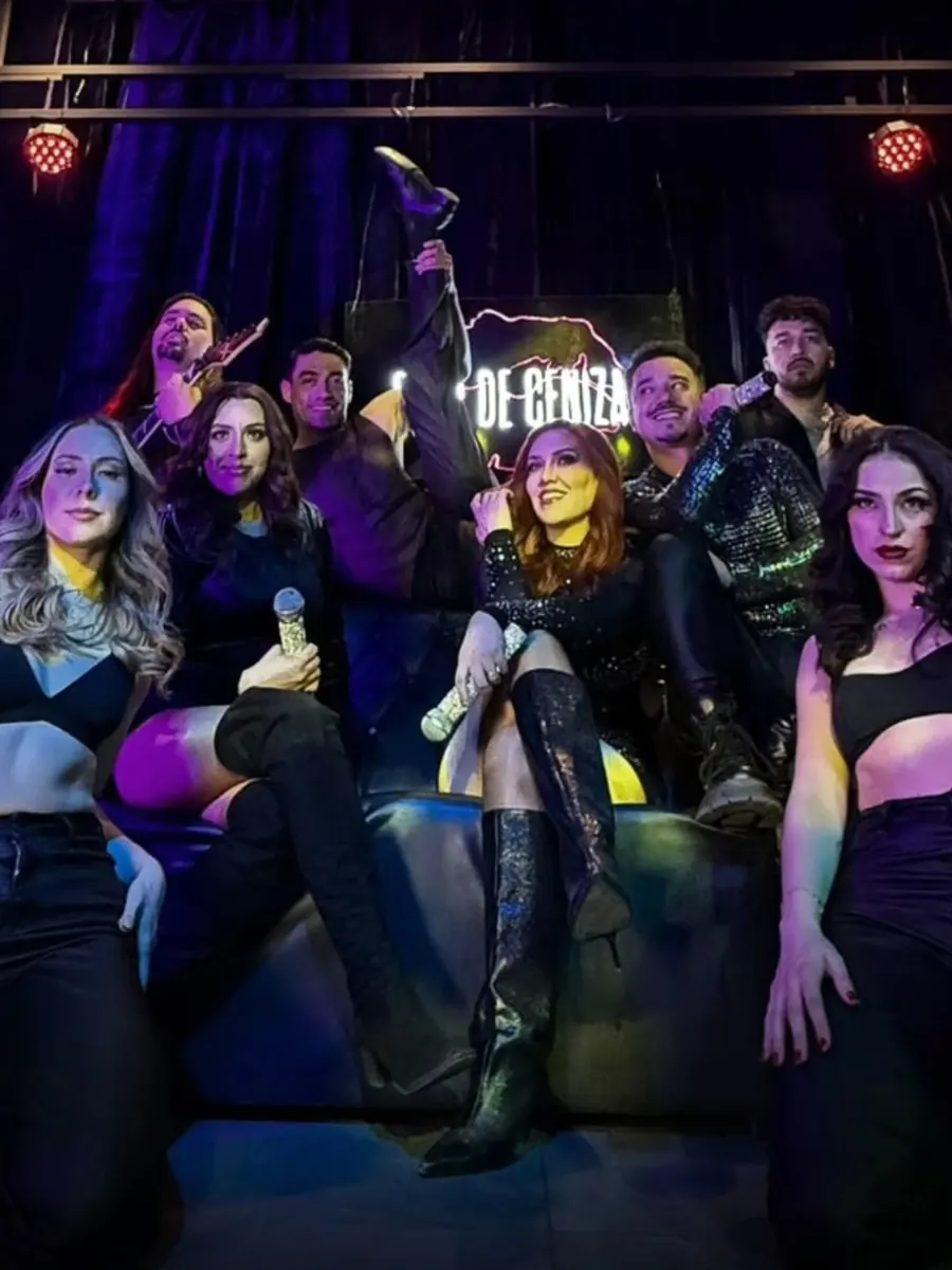 El elenco de VHS posando en un sillón sobre el escenario, con lentejuelas y botas altas